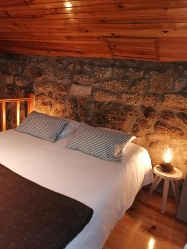 a bed in a room with a brick wall at Casa Encantada - Alvoco da Serra in Alvoco da Serra