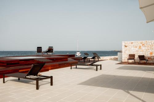 a group of chairs sitting on a patio overlooking the ocean at Le 3 di Tuccino in Polignano a Mare