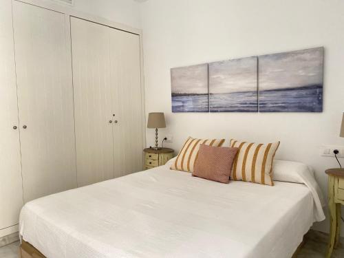 ein weißes Schlafzimmer mit einem Bett und einem Gemälde an der Wand in der Unterkunft Híspalis Catedral in Sevilla
