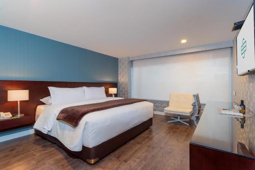 ein Hotelzimmer mit einem großen Bett und einem Stuhl in der Unterkunft Hotel Santa Barbara Boutique in Bogotá