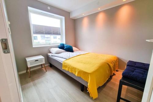 a bedroom with a bed with a yellow blanket on it at Aurora Central Apartment, Bodø in Bodø