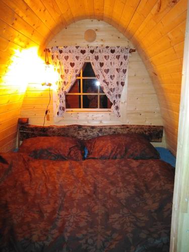a bed in a wooden room with a window at Wellness Kokořín in Kokořín