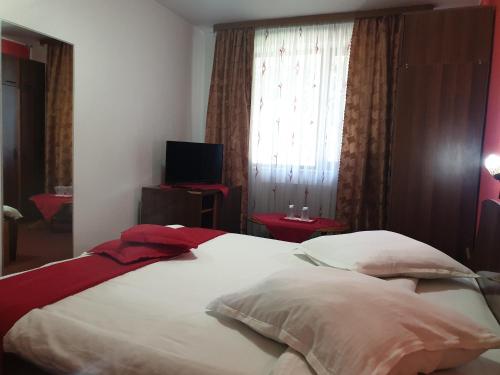 une chambre avec un grand lit blanc avec une fenêtre dans l'établissement Pensiunea ODN, à Scheia