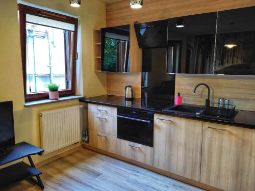 eine Küche mit Holzschränken, einem Waschbecken und einem Fenster in der Unterkunft SleepWell in Zielona Góra