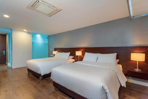 two beds in a hotel room with two lamps at Hotel Santa Barbara Boutique in Bogotá