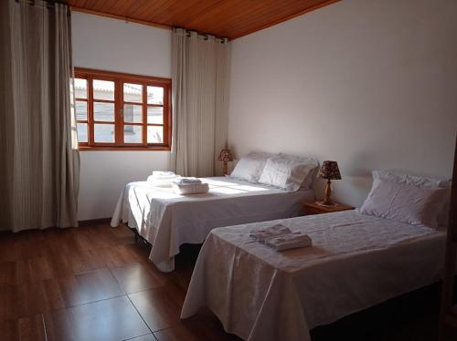 a bedroom with two beds and a window at Residencia Sao Miguel in Tiradentes