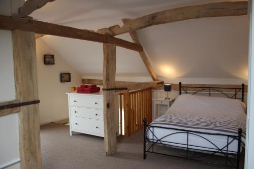 a bedroom with a bed and a dresser in a attic at Little Oaks in Stowmarket