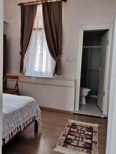 a bedroom with a bed and a window with a toilet at güneş pansiyon in Bozcaada