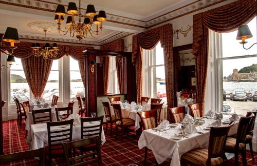 a dining room with tables and chairs and windows at Columba Hotel in Oban