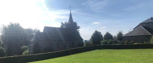 uma grande igreja com um campanário num quintal em Residenz Arens em Amblève