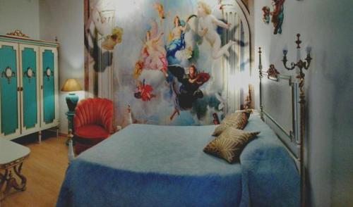 a bedroom with a blue bed in a room with a painting at Império Romano Guest House in Beja