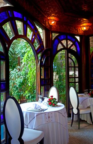 a dining room with white tables and chairs and windows at Palais Shéhérazade & Spa in Fès
