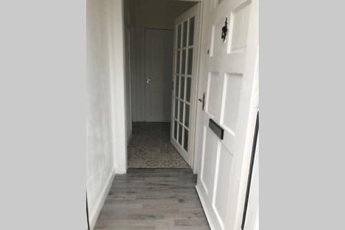 un pasillo con paredes blancas y una puerta abierta en Arthur Apartment, en Hawick