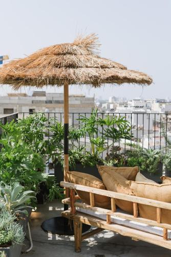 a bench under a straw umbrella on a balcony at AYA Boutique Aparthotel in Tel Aviv