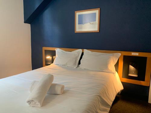 Elle comprend un grand lit avec des draps et des oreillers blancs. dans l'établissement Hôtel Montilleul - Villa Primrose, à Pau