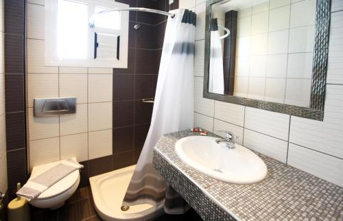 un bagno con lavandino, WC e specchio di Villa Elia a Limenas