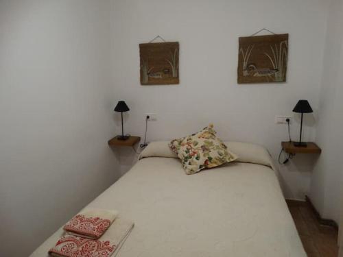 een slaapkamer met een wit bed met 2 lampen en 2 foto's bij El Herrador in Nájera