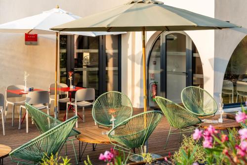 a patio with chairs and tables and an umbrella at Résidence de Diane - Toulouse in Toulouse