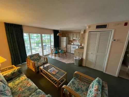 a living room with a couch and chairs and a kitchen at Breezy Palms Resort in Islamorada