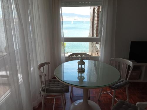 a table and chairs in a room with a large window at Estudio con vistas al mar en Baiona in Baiona
