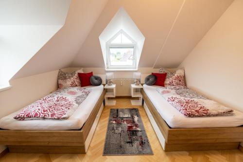 2 Betten in einem Dachzimmer mit Fenster in der Unterkunft Apartment Ella in Klagenfurt am Wörthersee