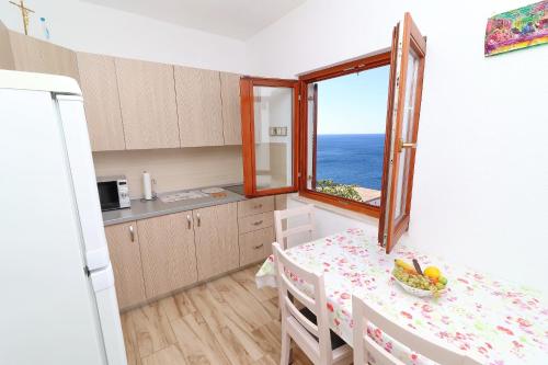 a small kitchen with a table and a window at Seaside Apartments Hrkać in Orebić