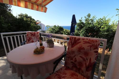 a table and chairs on a balcony with the ocean at Seaside Apartments Hrkać in Orebić