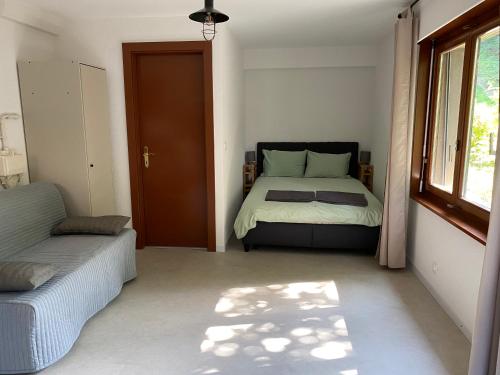 1 dormitorio con cama, ventana y puerta en Joli Studio près des Bains de Lavey, en Savatan
