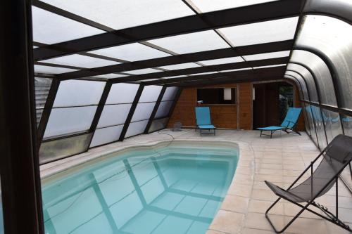une piscine avec un toit-terrasse et des chaises dans l'établissement Ker-Loën, à Val Couesnon