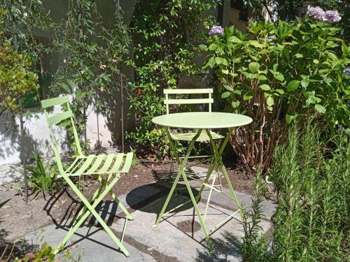 two green chairs and a table and chairs in a garden at LA TICINELLA in Losone