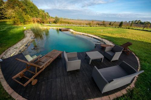 a pool with a deck with chairs and a table at Lesence Major in Lesencetomaj