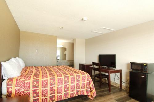 a bedroom with a bed and a desk and a television at Town and Country INN in Rogers