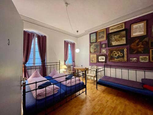 two beds in a room with paintings on the walls at Pension Jeske Heidelberg in Heidelberg