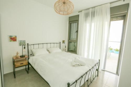 Un dormitorio con una gran cama blanca y una ventana en פנינה באכזיב- מול הים- achzivacation en Nahariyya