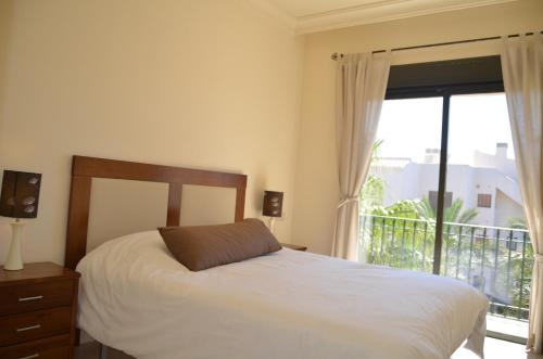a bedroom with a bed and a window with a balcony at Roda Golf Resort 5508 - Resort Choice in Roda