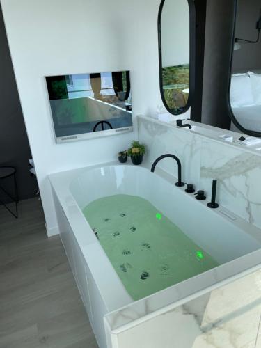 een witte badkamer met een bad en een spiegel bij Per Sea in Koksijde