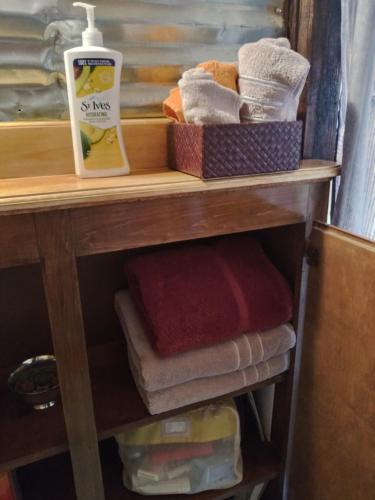 a wooden shelf with towels and a bottle of soap at La loma del chivo Llc Stone Cottage alternative building in Marathon