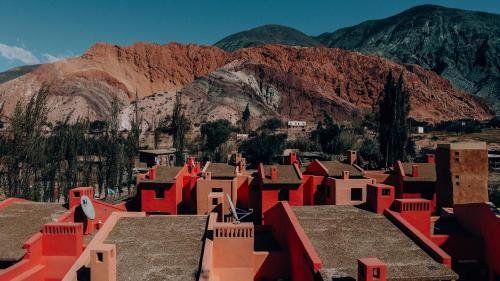 a group of red buildings with mountains in the background at Colores de Purmamarca in Purmamarca