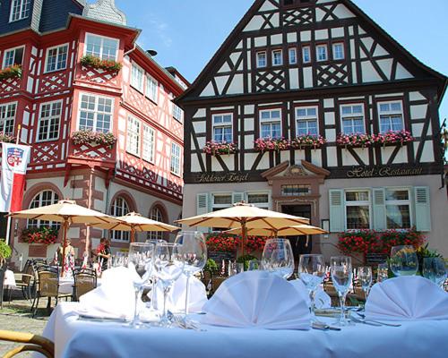 a table with glasses and umbrellas in front of a building at Hotel Restaurant Goldener Engel in Heppenheim an der Bergstrasse