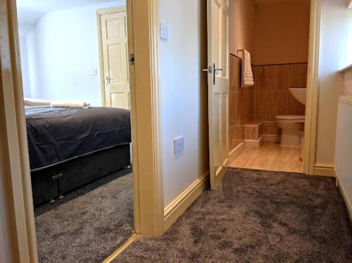 a bedroom with a bed and a bathroom with a toilet at Racecourse Cottage in Doncaster