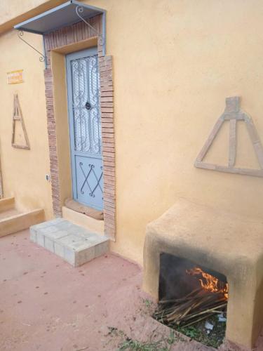 a fire in front of a building with a door at Le petit Jardin in Demnat