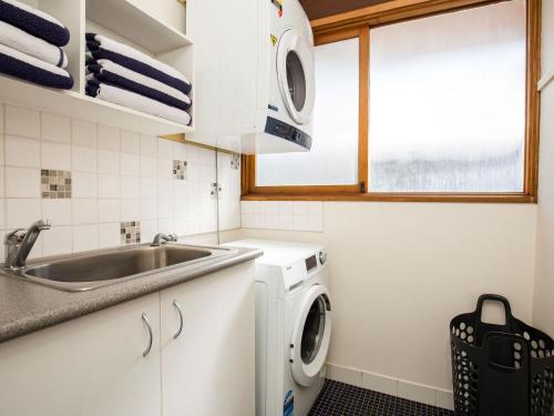 a kitchen with a sink and a washing machine at Beach Street Residence Huskisson in Huskisson