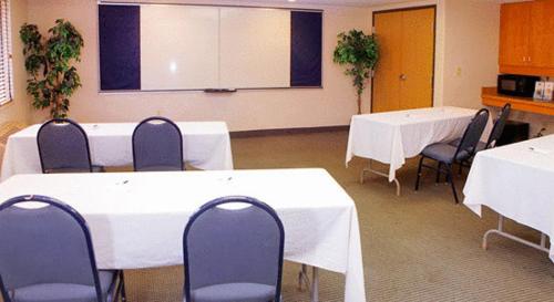 a conference room with white tables and blue chairs at AmericInn by Wyndham Madison South in Madison