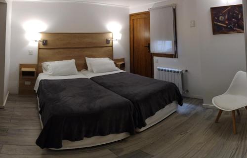 ein Schlafzimmer mit einem großen Bett und einem weißen Stuhl in der Unterkunft Casa Laura Bariloche in San Carlos de Bariloche