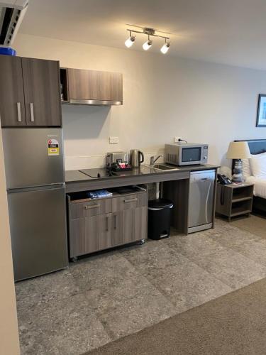 a kitchen with stainless steel appliances in a room at Ramada Suites by Wyndham Queenstown Remarkables Park in Queenstown