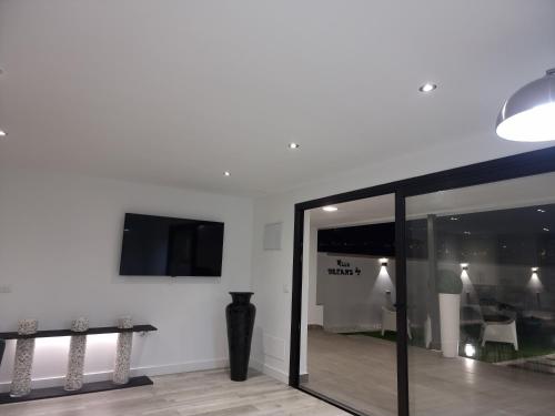 a living room with a tv and a glass door at ViLLA DREAMS JF in Arona