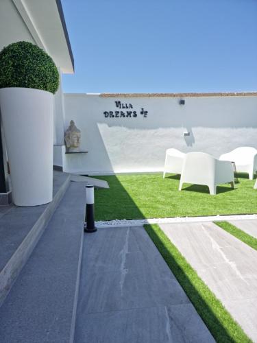 a patio with grass and white furniture in a building at ViLLA DREAMS JF in Arona