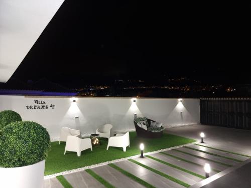 a rooftop patio at night with white furniture and lights at ViLLA DREAMS JF in Arona