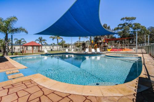 uma grande piscina com um parque infantil ao fundo em Paynesville Holiday Park em Paynesville