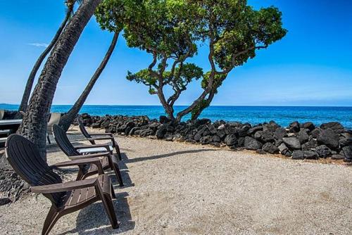 three chairs sitting on the beach near the ocean at Kona Isle E23 in Kailua-Kona
